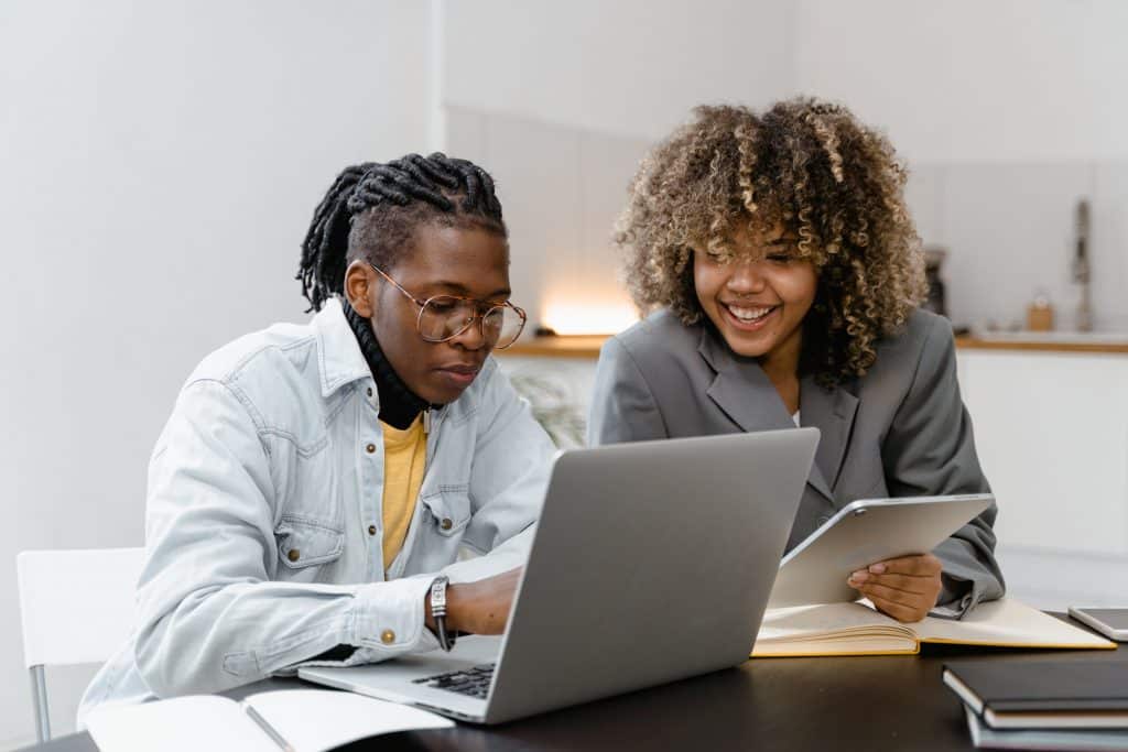 Two colleagues working together at a desk with laptop and tablet